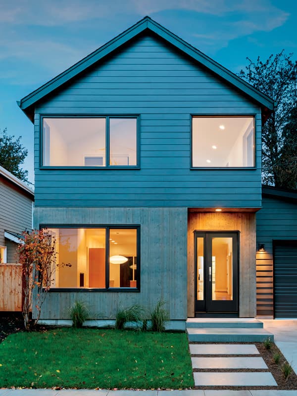 Modern home with black entry door at dusk