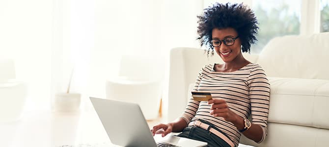 a woman sits on the floor with her laptop shopping for new windows