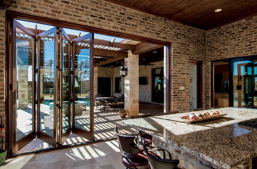 Interior of European style kitchen that looks out to an outdoor space through slightly opened bifold doors