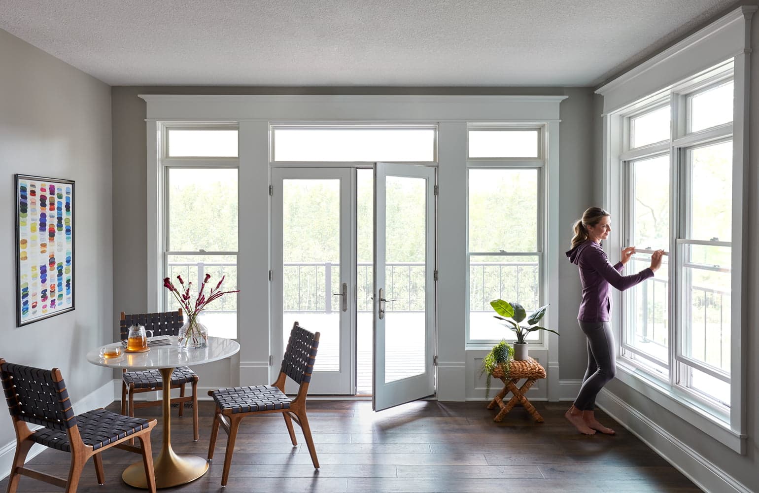 A four-season room with white windows and a hinged door making up three of the four walls.