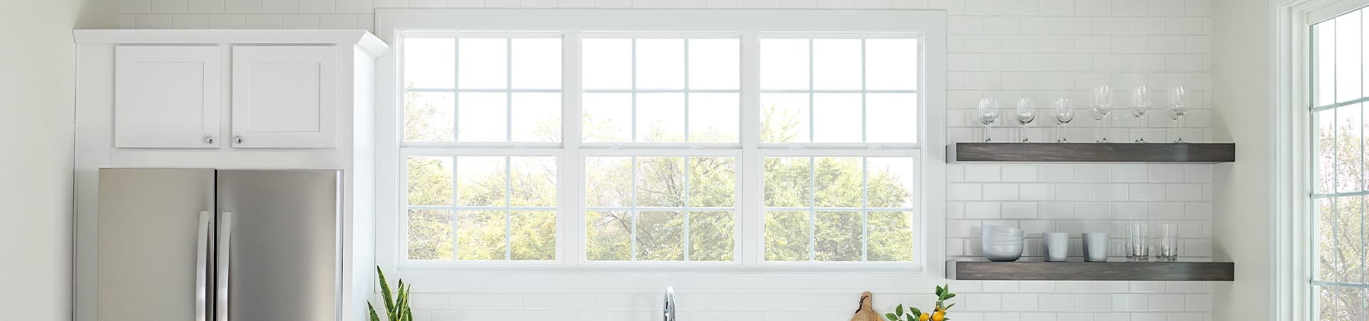 three single-hung windows in a white kitchen with orange barstools