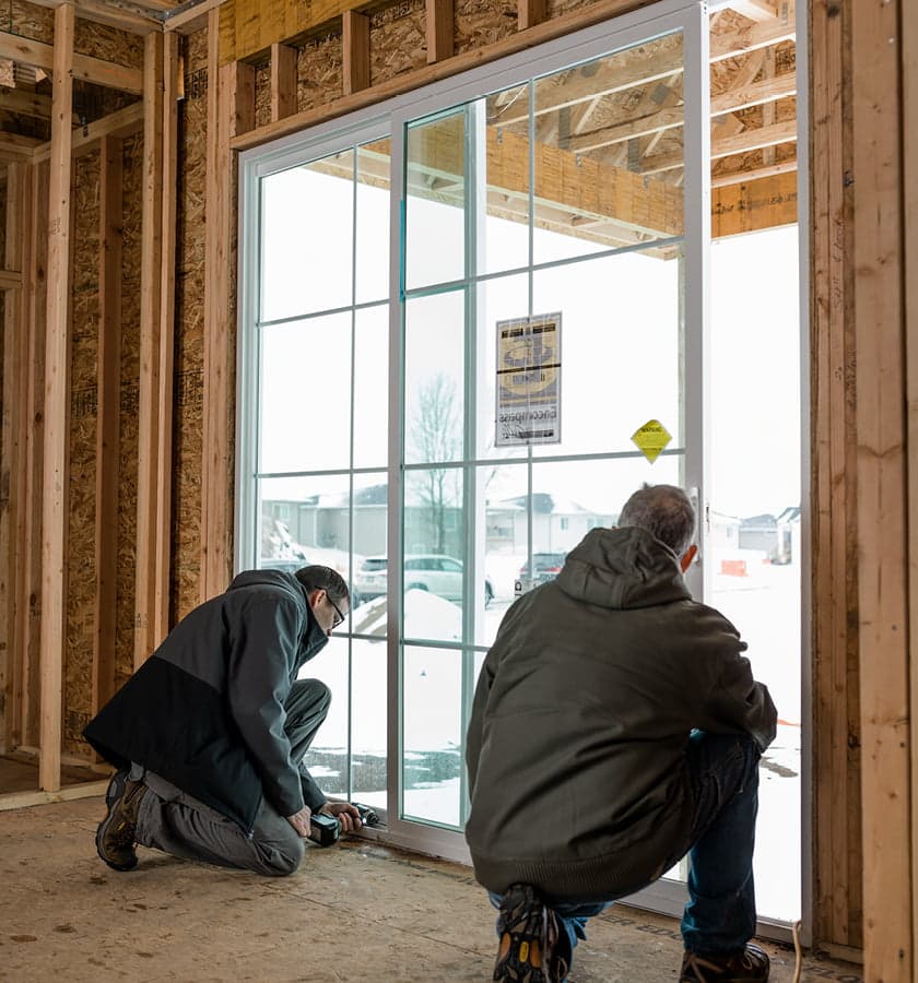 two construction workers installing a vinyl sliding patio door