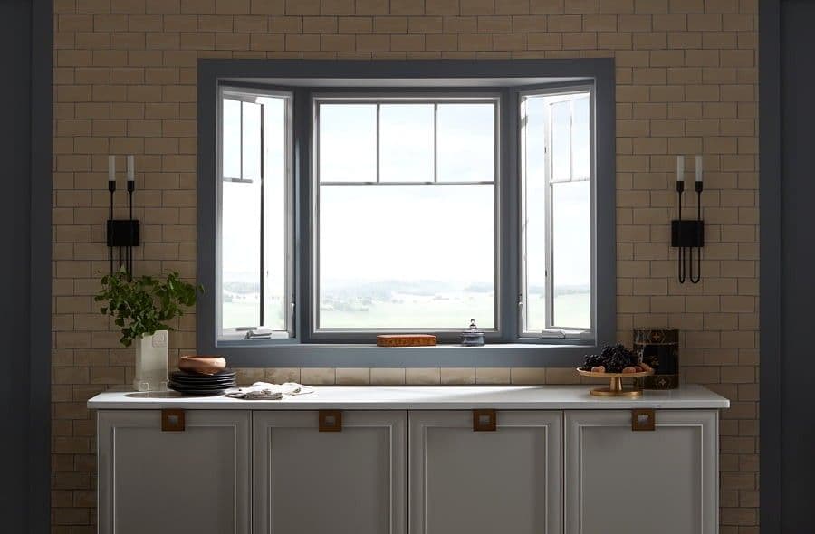 Bay window with partial grilles above a white table and accented with sconces