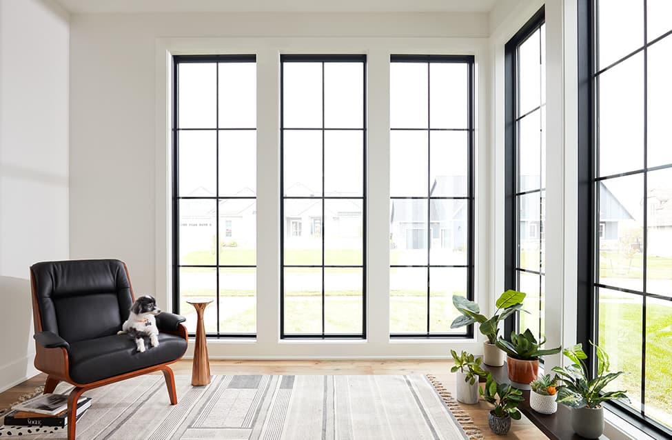 a minimalist contemporary sunroom surrounded by black tall picture windows
