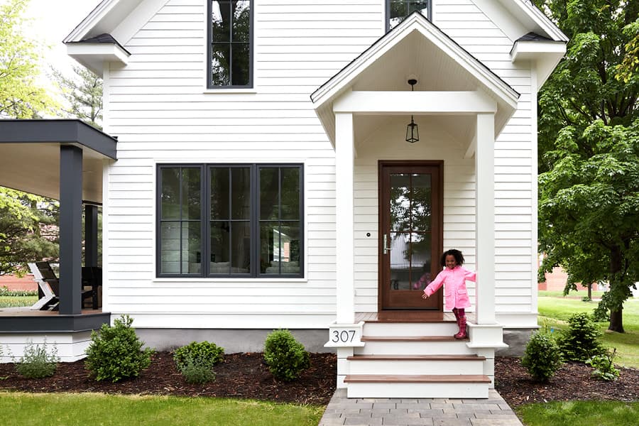 White Farmhouse Home with Wood Entry Door and Deck