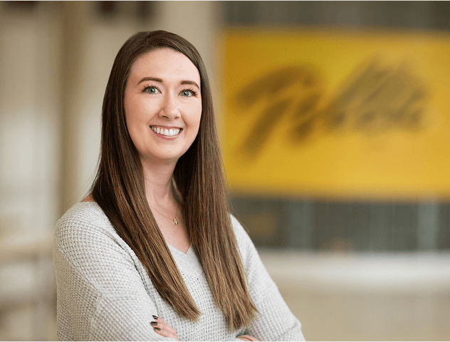 a woman with long brown hair is smiling in front of a Pella sign