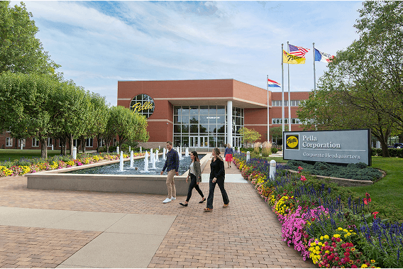 Three people are walking in front of a water feature that is part of the Pella Corporation entrance.