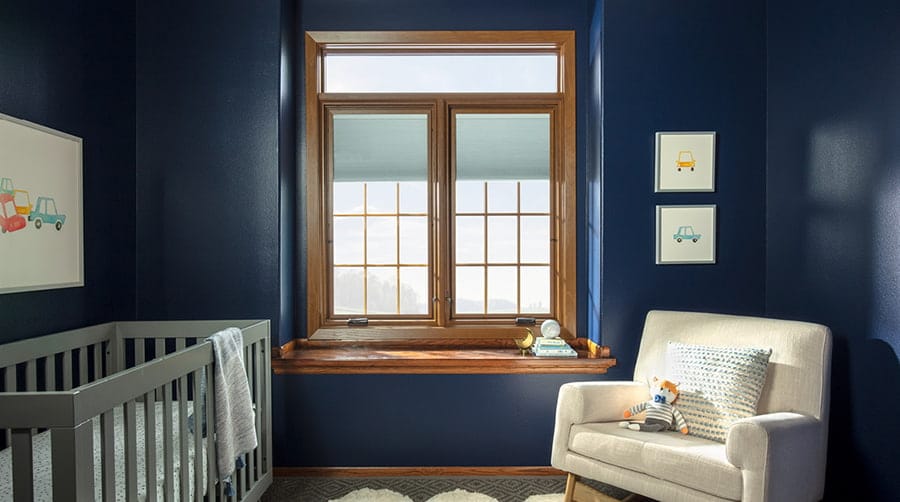 child's nursery painted in a dark blue with wood casement windows featuring blinds-between-the-glass and grilles