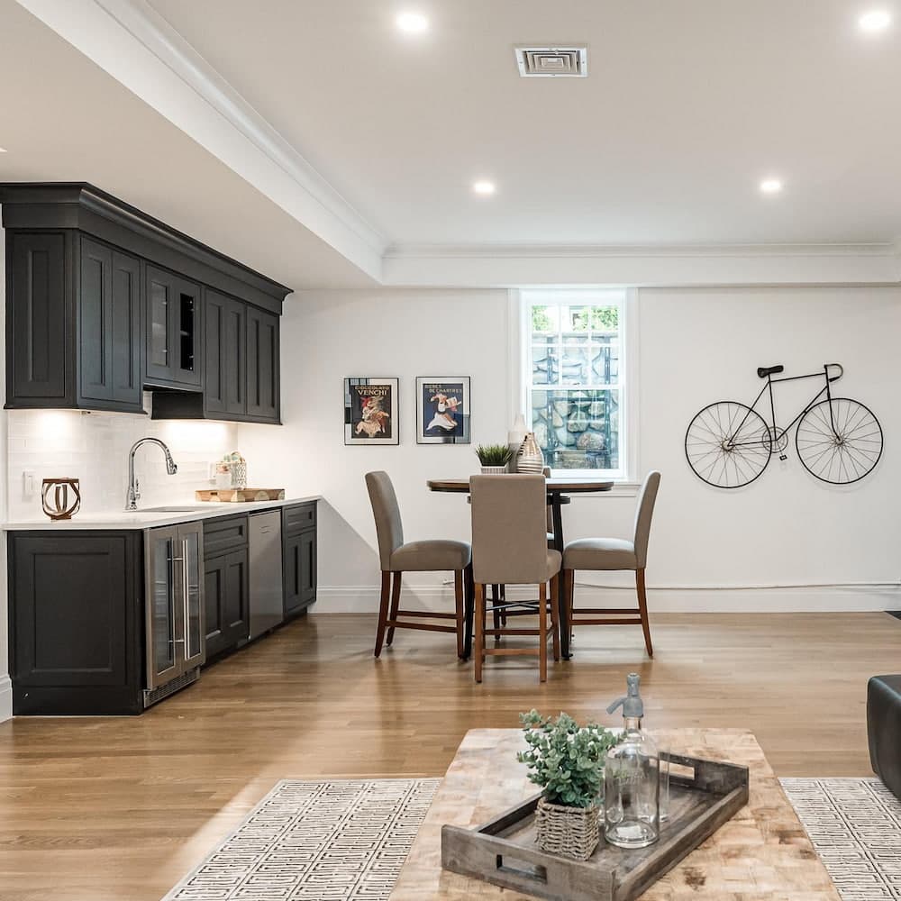 A basement features a wet bar and dining area with an egress window in the background.