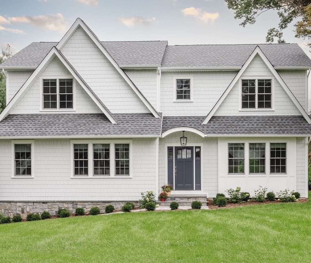 A white house with double-hung windows and a blue front door features traditional style.