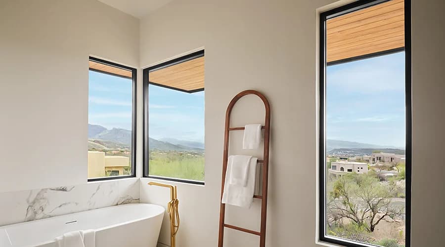 Sunny weather seen through large bathroom windows with mountain views and clear blue skies.