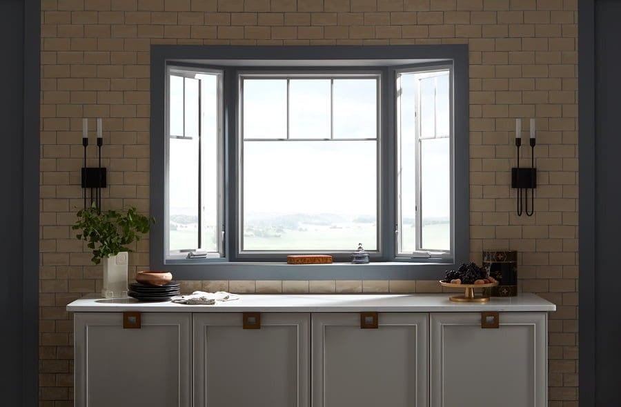 Bay window with partial grilles above a white table and accented with sconces