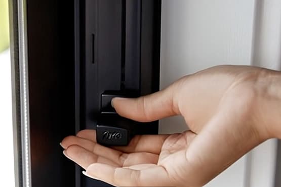 A woman's hand is opening a black casement window with Pella's Easy-Slide Operator.