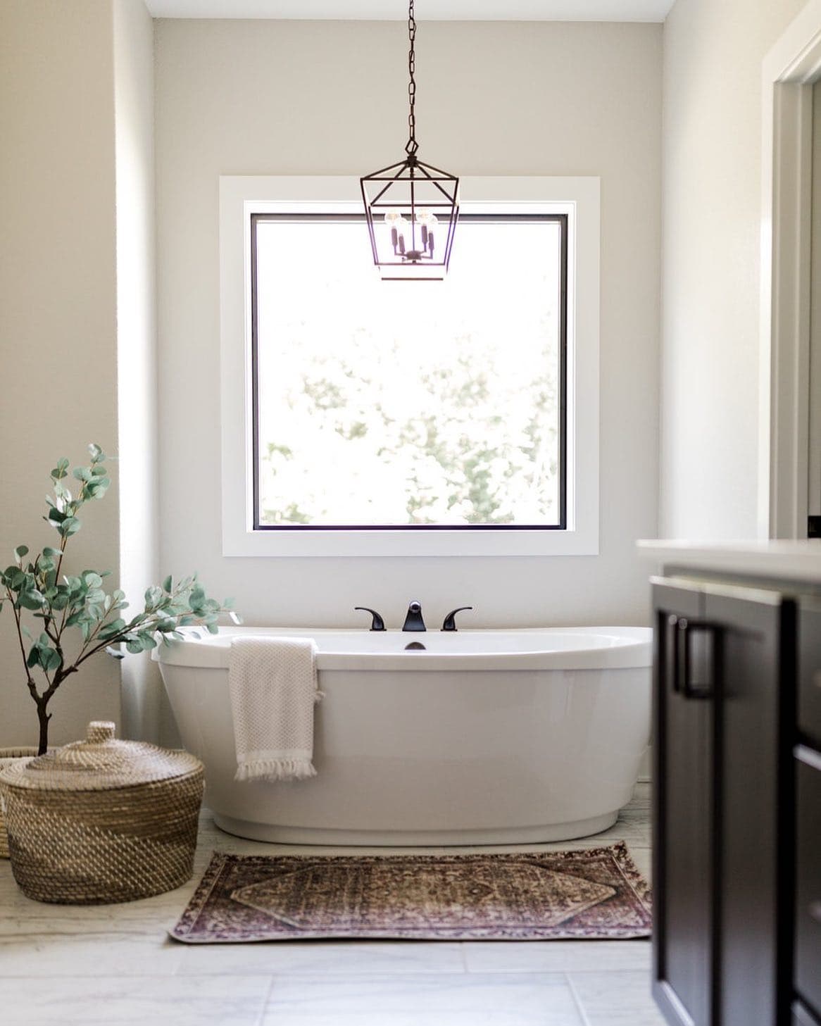 Square Picture Window Enhances Serene Bathroom Design Square picture window over bathtub lets light into spa like bathroom